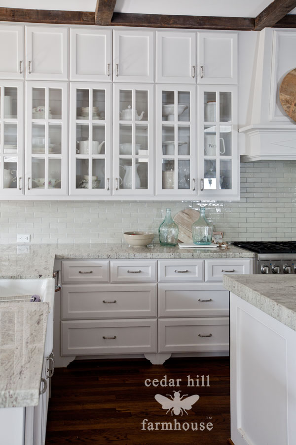 White kitchen cabinets with store glass doors on top