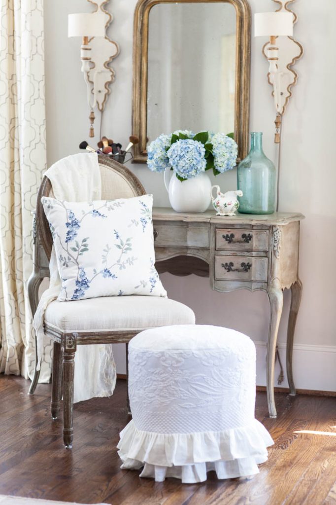 blue floral embroidery pillow on chair by vanity
