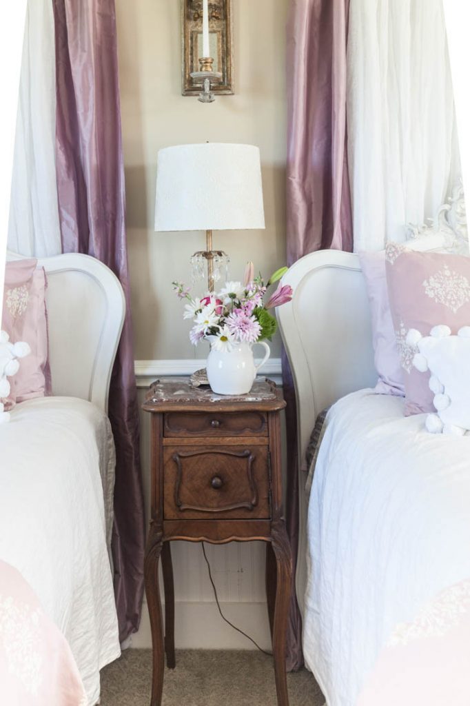pink curtains behind bed and wall candle sconce