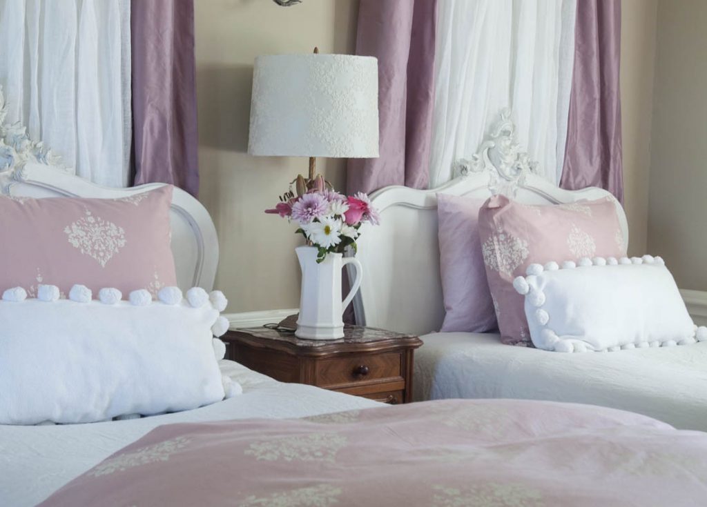 pink curtains behind bed and flowers